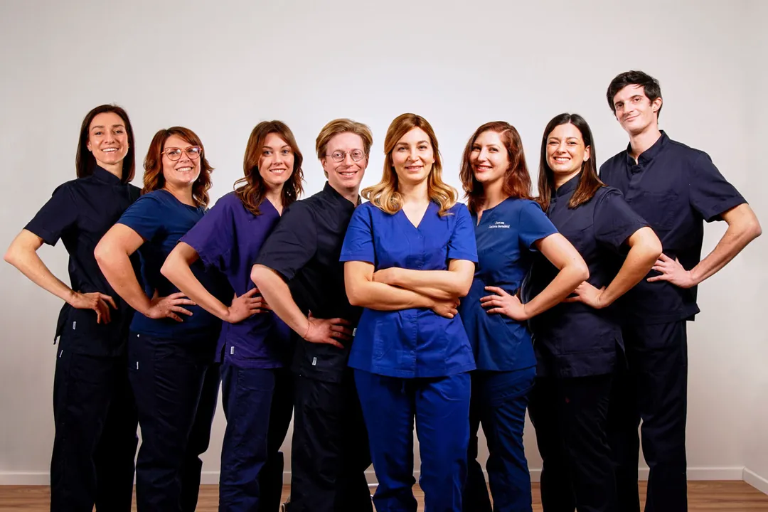 Otto persone della squadra in divisa blu notte, blu e viola, in piedi e sorridenti, mani sui fianchi