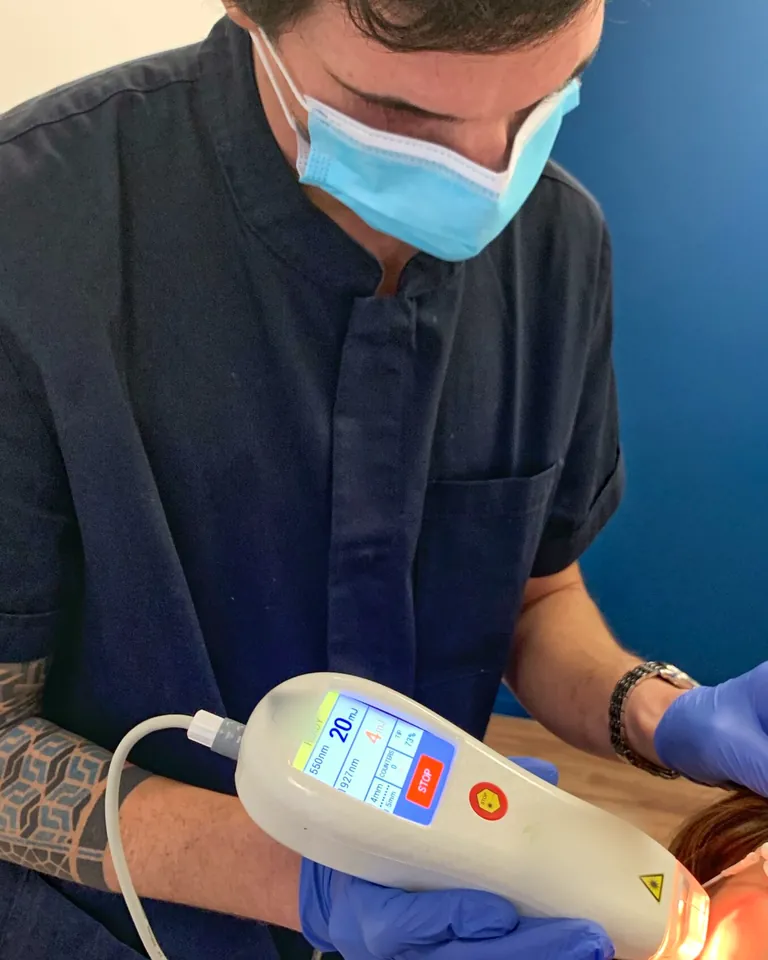 Il laser frazionato in uso: l'operatore con la mascherina guida il manipolo, lo schermo acceso